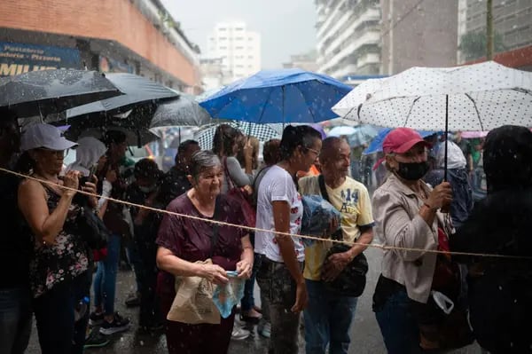 Venezolanos esperan en fila bajo una fuerte lluvia para emitir su voto fuera de un colegio electoral durante las primarias de la oposición en Caracas, Venezuela.