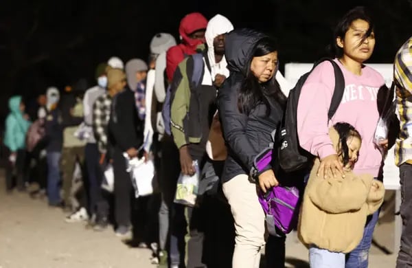 Inmigrantes que solicitan asilo en Estados Unidos hacen cola para ser procesados por agentes de la Patrulla Fronteriza estadounidense a primera hora de la mañana tras cruzar a Arizona desde México el 10 de mayo de 2023 en Yuma, Arizona.