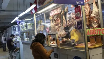 Un comprador compra carne a un carnicero en un mercado de Lima, Perú.