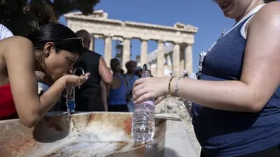 Turistas en una fuente de agua en el yacimiento arqueológico de la Acrópolis, durante condiciones climáticas de calor extremo, en Atenas en julio de 2023. 