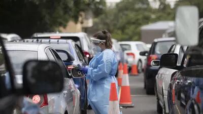 Profissional de saúde atende pessoa dentro de um carro para testagem de Covid-19 na cidade de Sydney