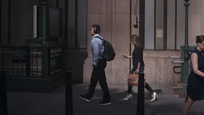 Pessoas passando em uma rua. Foco em um homem usando tênis da marca Nike com roupa típica de escritório