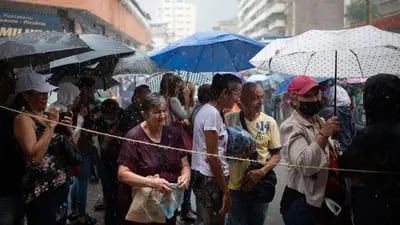 Venezolanos esperan en fila bajo una fuerte lluvia para emitir su voto fuera de un colegio electoral durante las primarias de la oposición en Caracas, Venezuela.