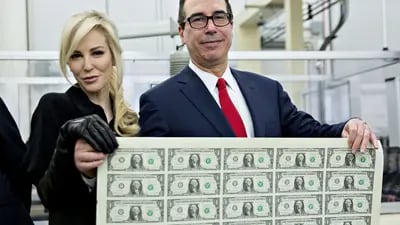 Homem moreno e mulher loira seguram uma folha de impressão de dólares
