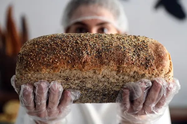 Un trabajador sostiene una barra de pan blanco con semillas en una panadería en Beirut, Líbano, el jueves 31 de marzo de 2022.