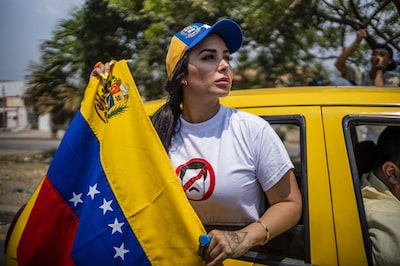 Un manifestante sostiene una bandera venezolana mientras conduce cerca del puente internacional Simón Bolívar en Cúcuta, Colombia.