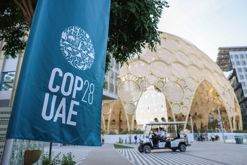 Imagem de uma bandeira azul clara com os dizeres "COP28 UAE"