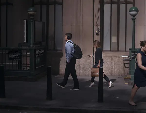 Pessoas passando em uma rua. Foco em um homem usando tênis da marca Nike com roupa típica de escritório